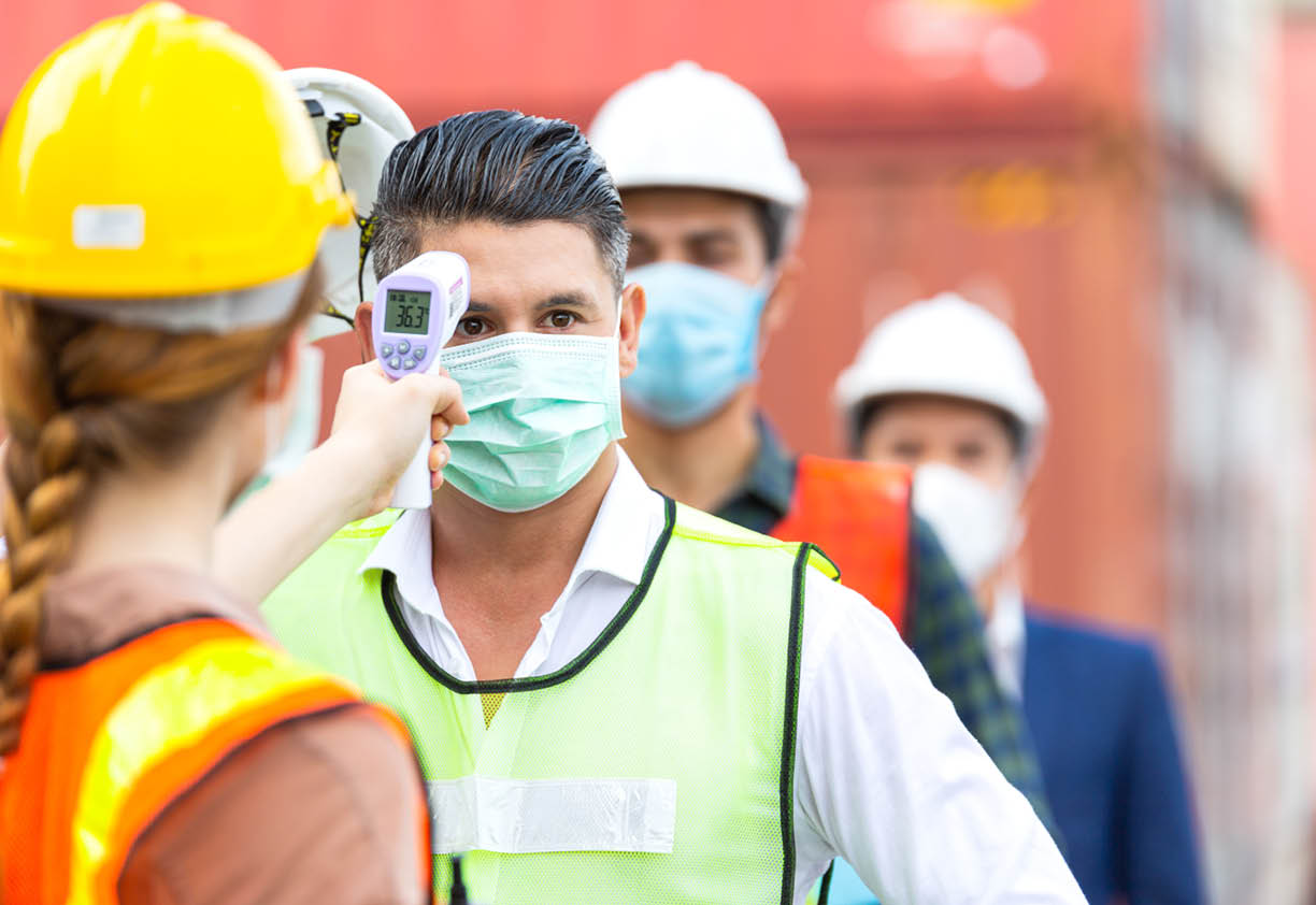 Female worker scanning fever temperature with digital thermometer to construction site staff wearing hygiene face mask protect from Coronavirus or COVID-19  New Normal working life adaptation in 2020
