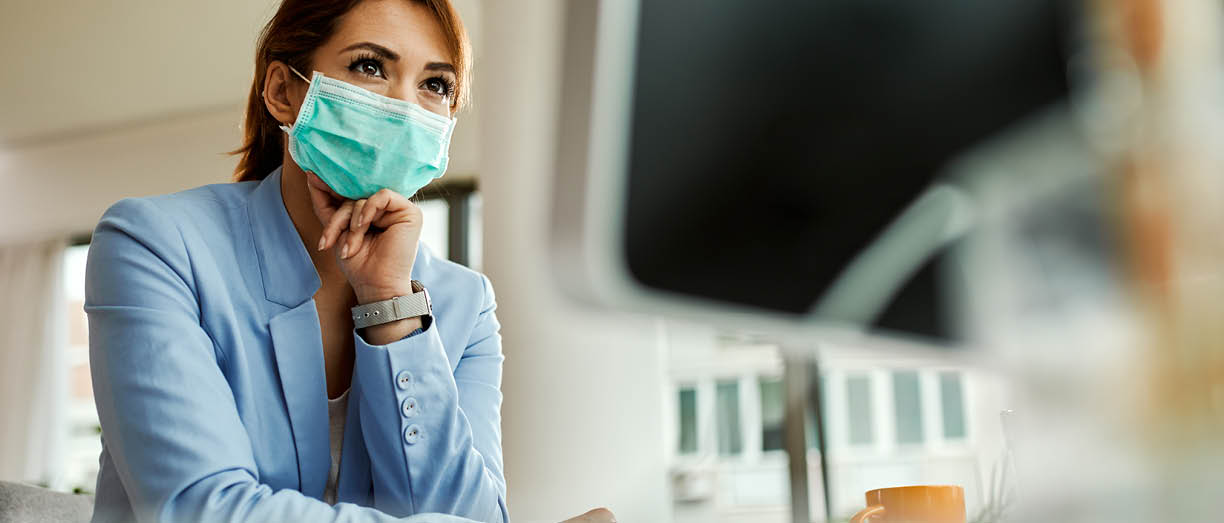Low angle view of businesswoman with face mask working on desktop PC in the office  