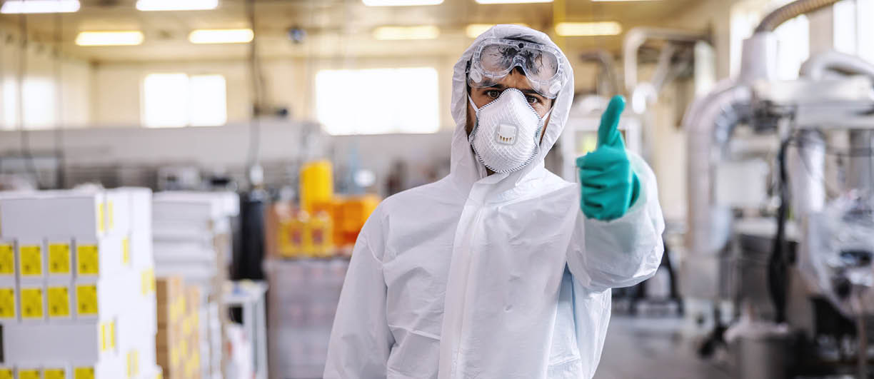 Man in protective suit, mask and gloves standing in food production factory and showing thumbs up  He just disinfected whole facility from covid-19   corona virus 