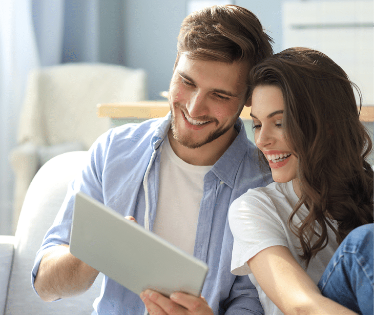 Young couple watching media content online in a tablet sitting on a sofa in the living room 