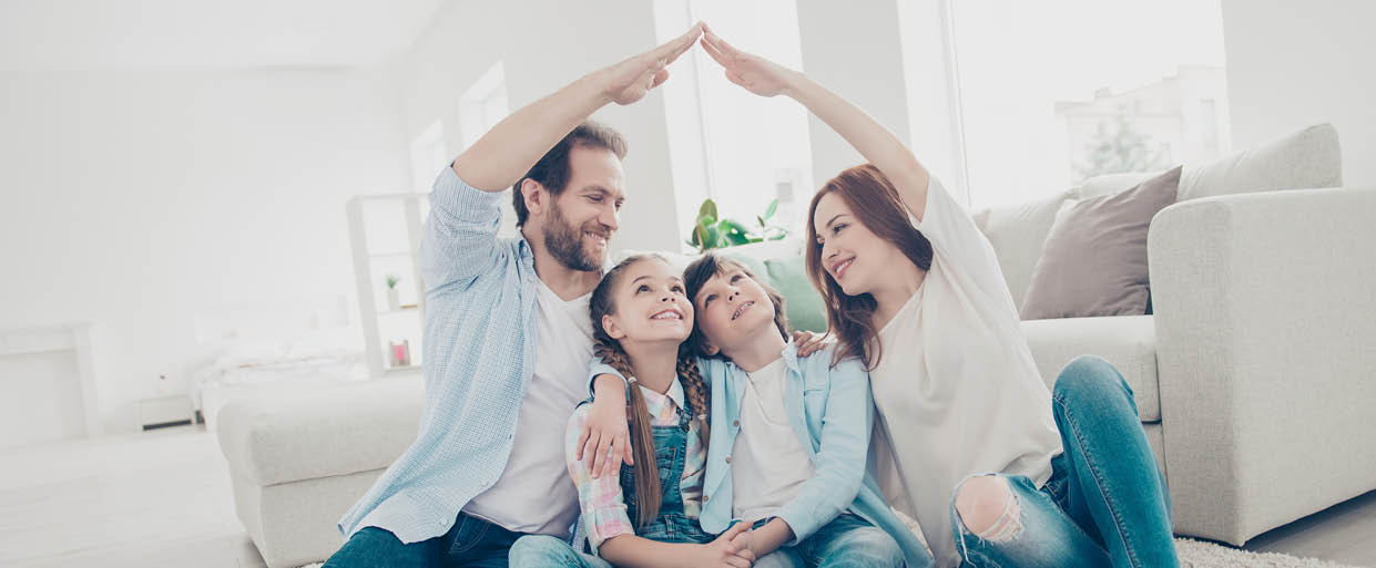 New building residential house purchase apartment concept  Stylish full family with two kids sitting on carpet, mom and dad making roof figure with hands arms over heads